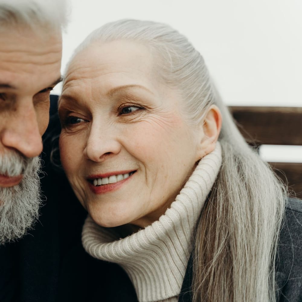 An older couple sitting close together, smiling